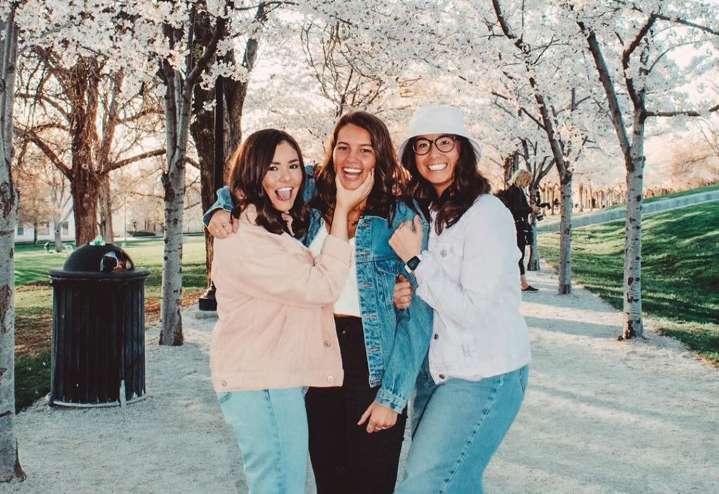 Three women standing under cherry trees
